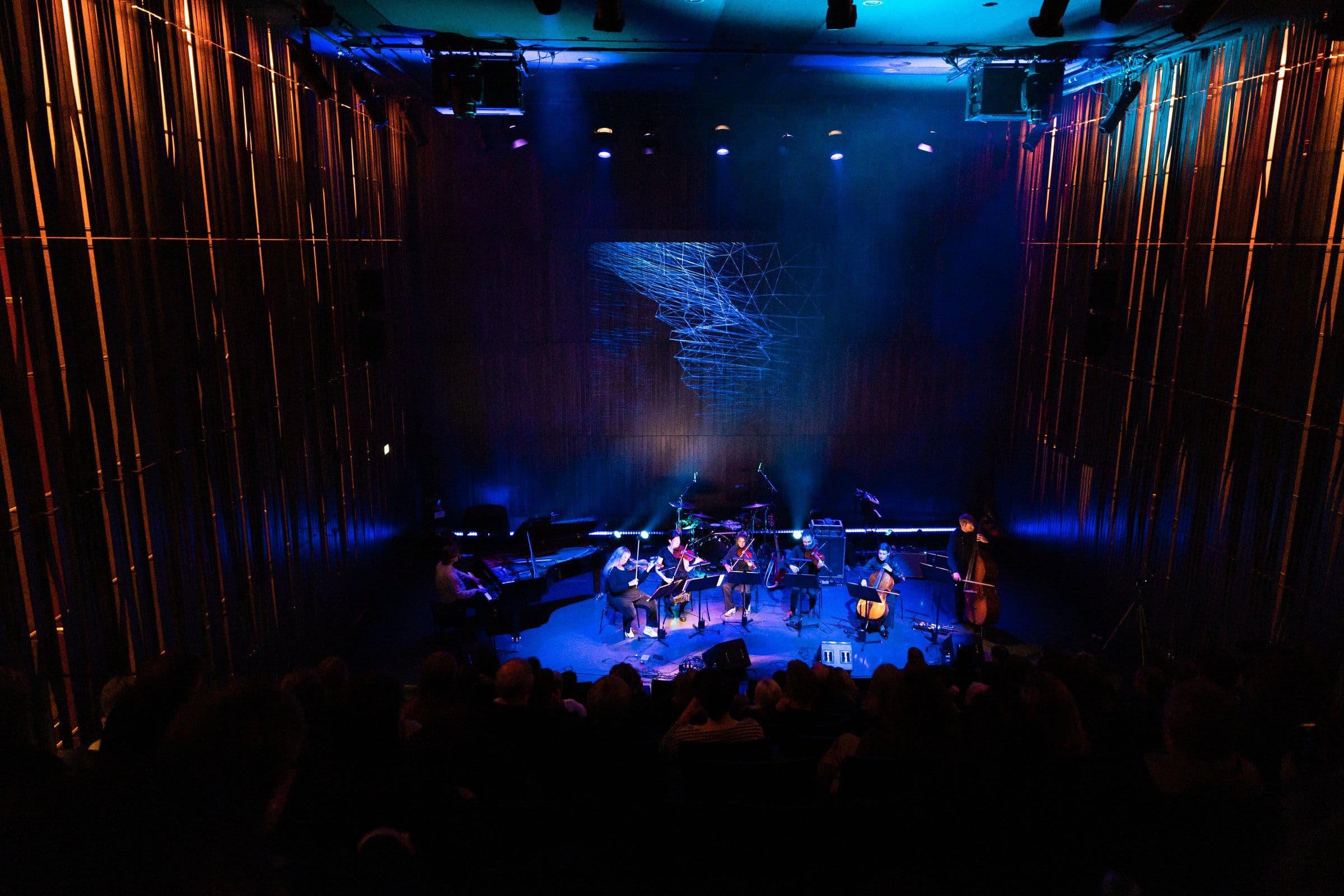 a group of people are playing instruments on a stage in front of a crowd .