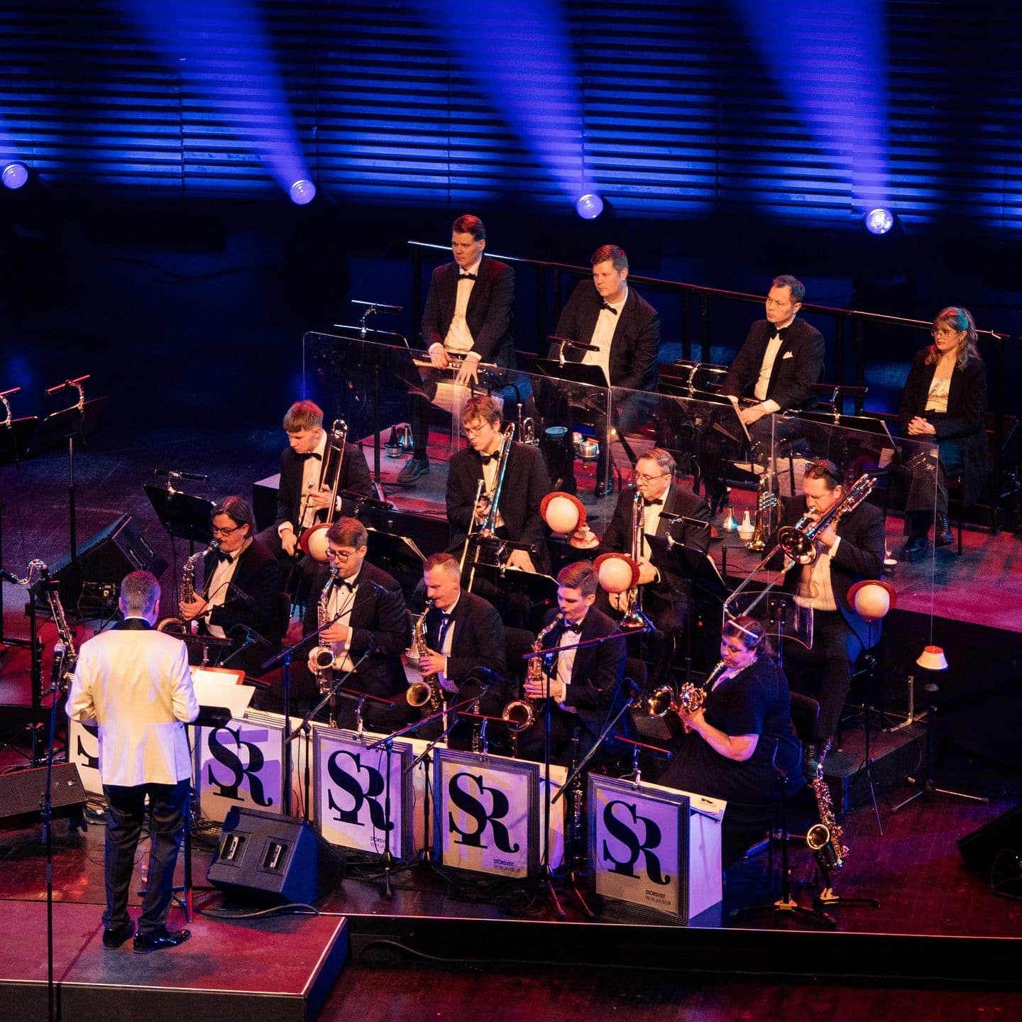 a man is standing in front of an orchestra on a stage .