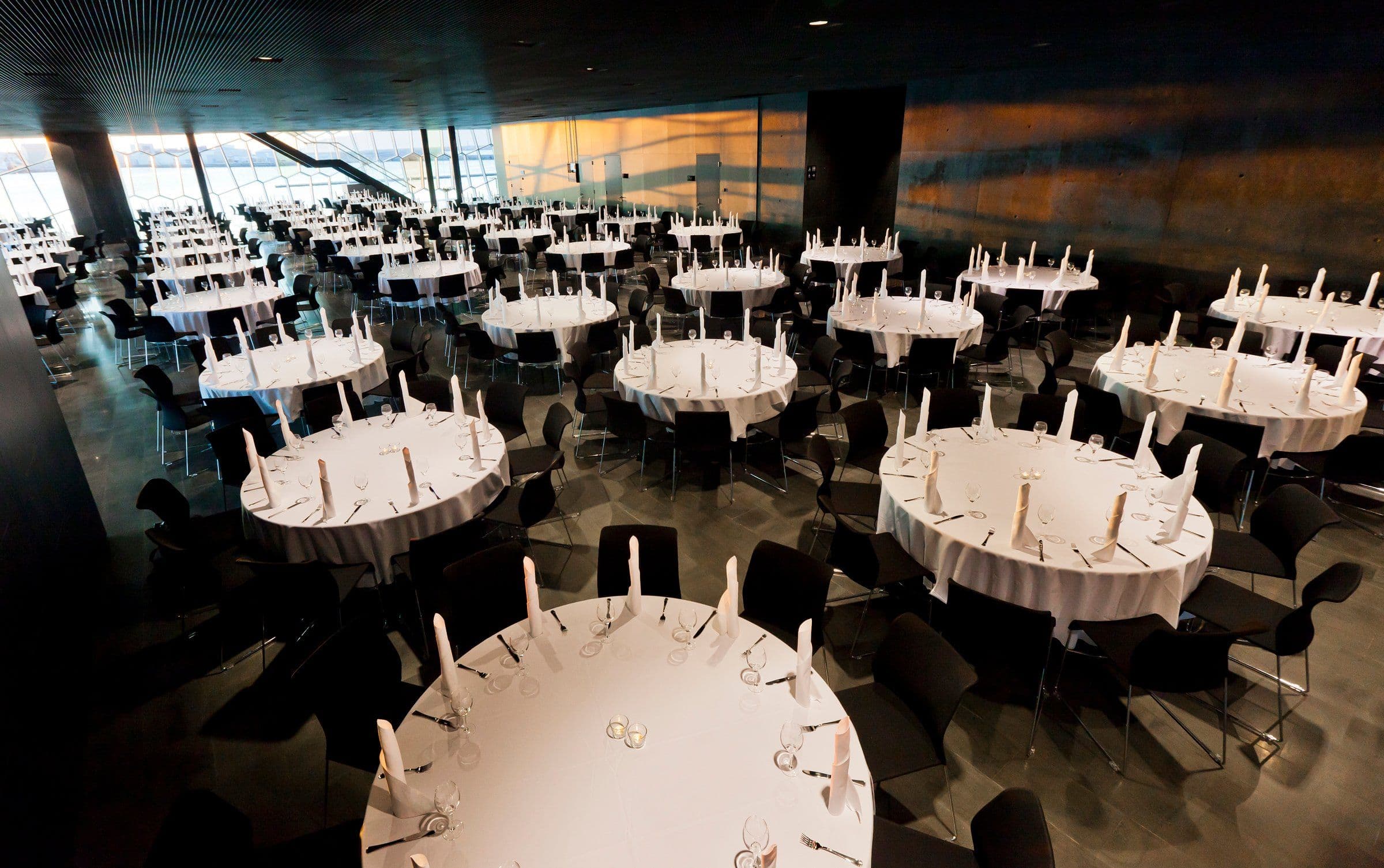a large room filled with tables and chairs set up for a banquet .