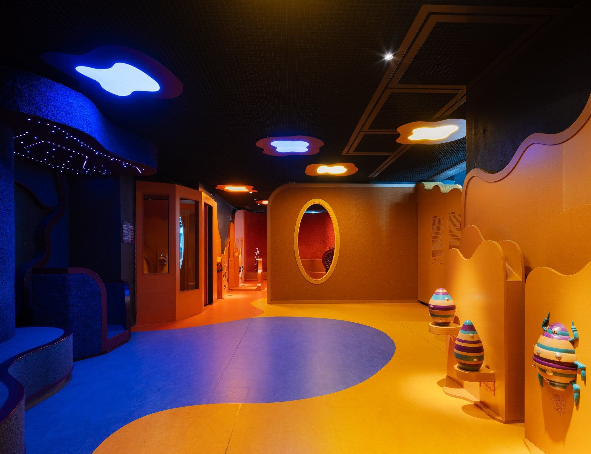 a hallway with a lot of colorful objects on the floor and ceiling .