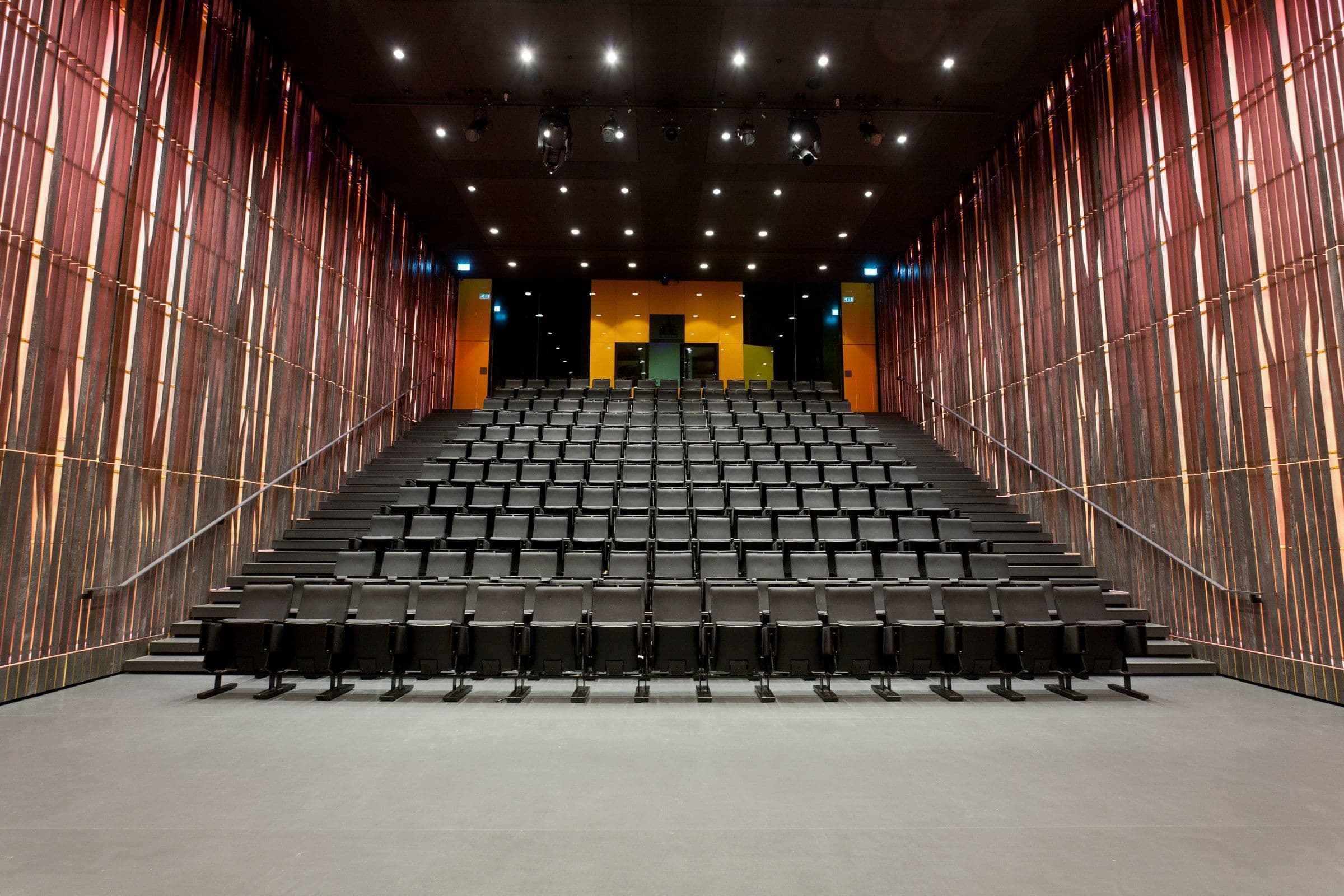 an empty auditorium with rows of seats and stairs leading up to the stage .